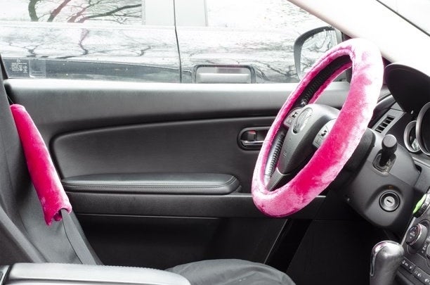Pink velvet steering wheel cover and matching seatbelt in car with black interior