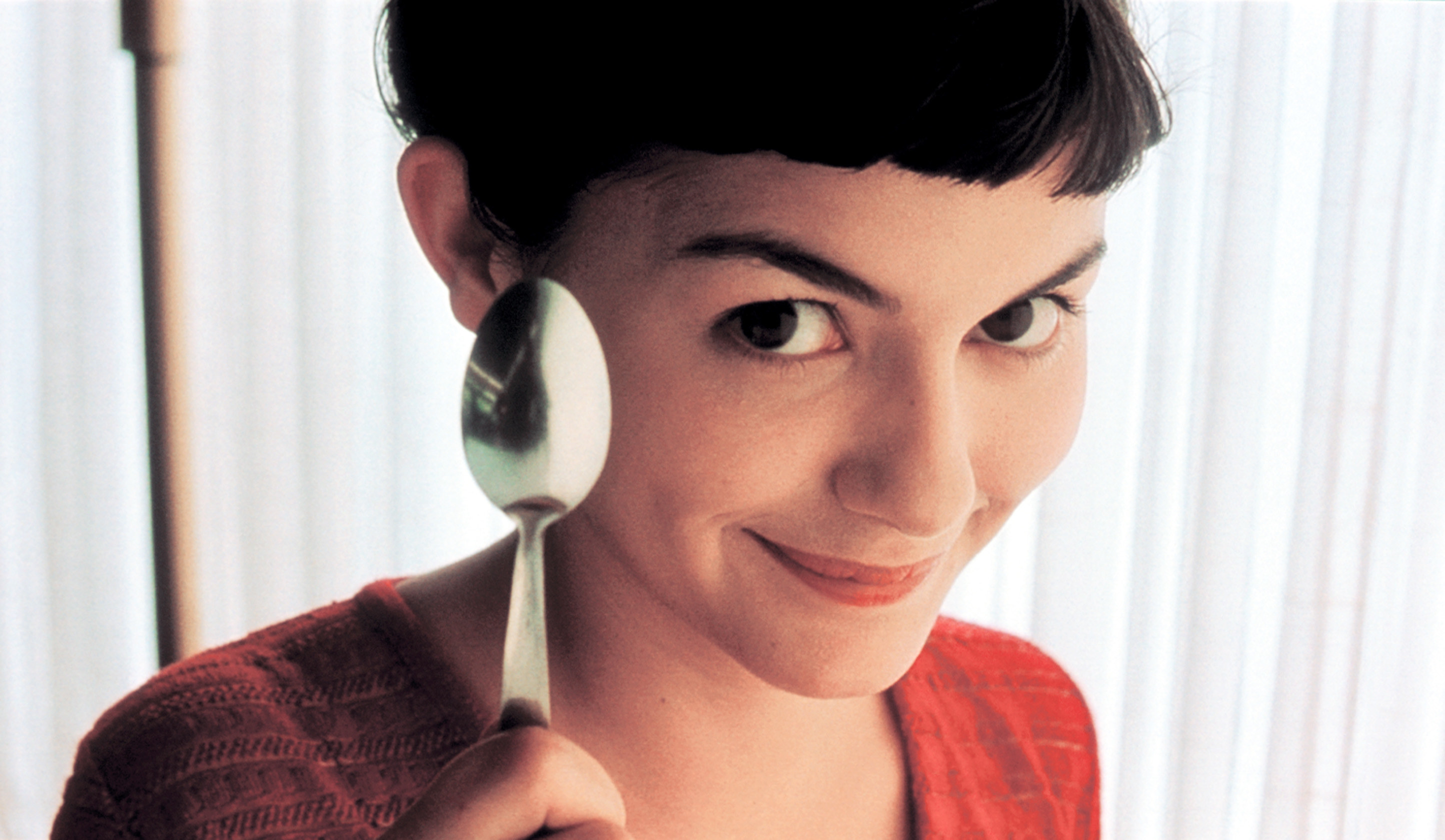 Audrey Tatou holds a spoon and looks mischievously at the camera