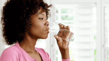 woman drinking water and expressing happiness