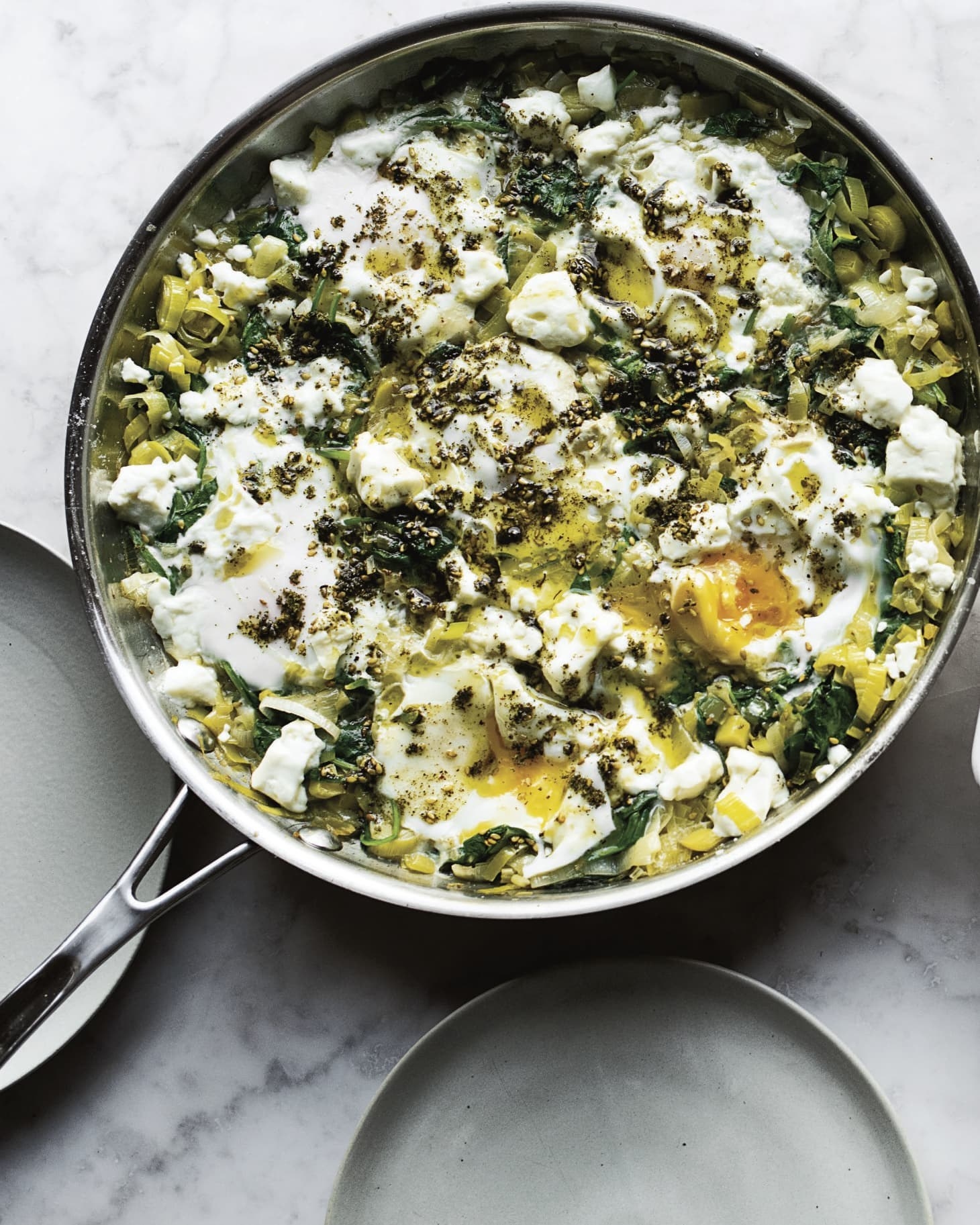 A skillet of leeks and braised eggs with za&#x27;atar seasoning