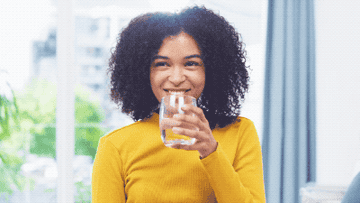 Woman taking a small sip of water an smiling