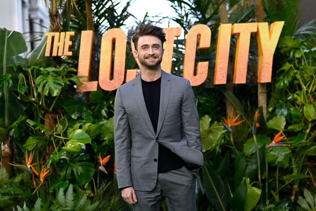 Daniel Radcliffe in front of a sign for &quot;The Lost City&quot; movie