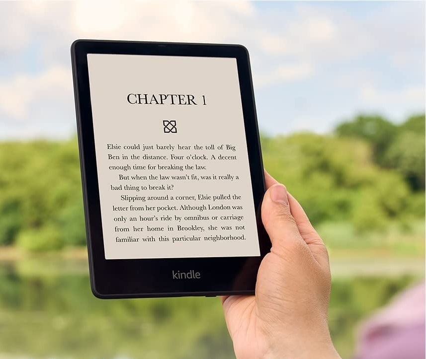 someone using the kindle paperwhite e-reader outdoors