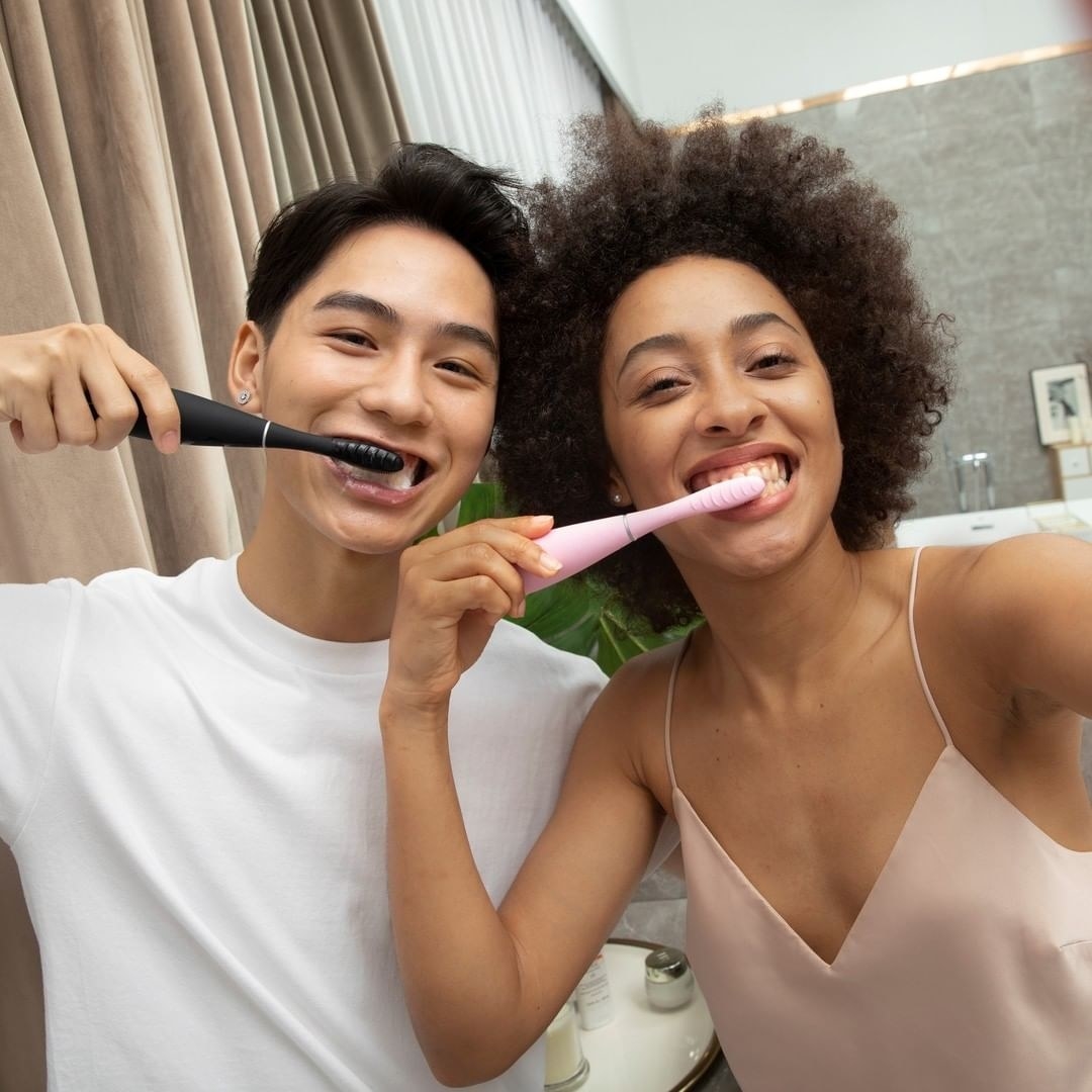a pair of people using the sonic toothbrushes