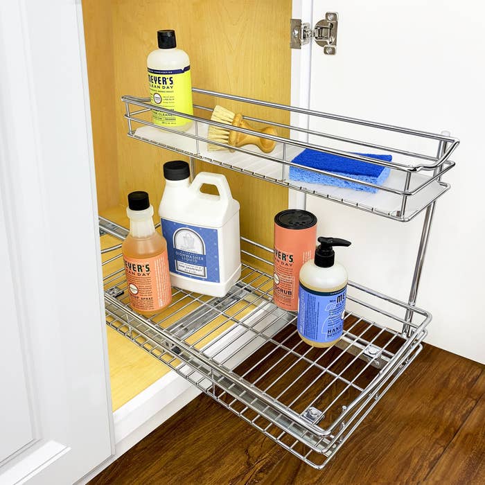 the pull out drawer under a kitchen sink with cleaning products on it