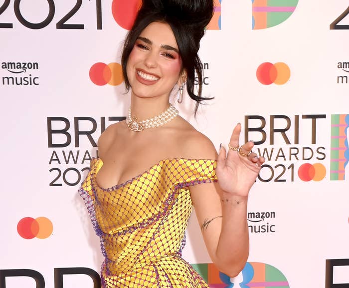 Dua smiles and waves at an event