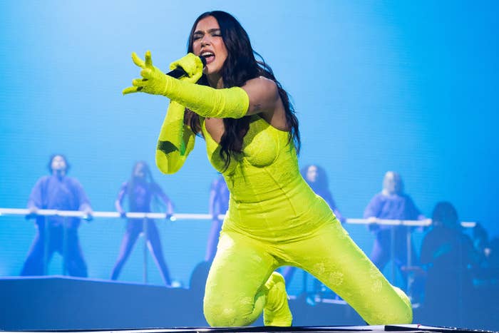 Dua performs on stage in a neon green jumpsuit and matching gloves