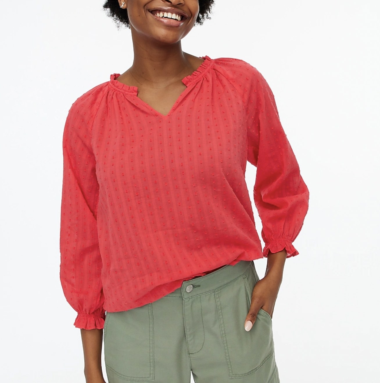 Model wearing the peach top slightly tucked into green pants