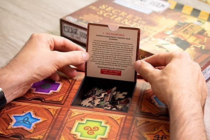A person&#x27;s hands flipping a door open on the puzzle box to reveal a clue