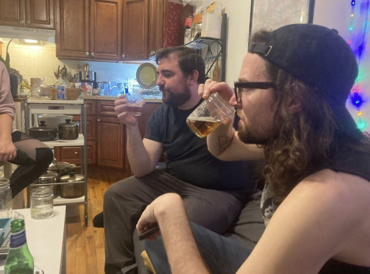 two men sniff and look at their glasses of fake beer
