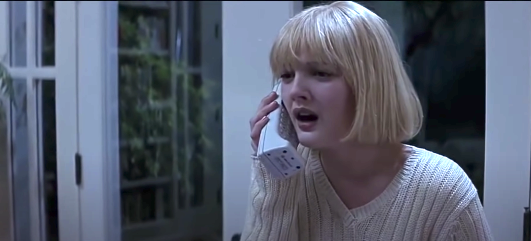 Drew Barrymore in Scream with a blonde bob haircut and a large cordless house phone to her ear