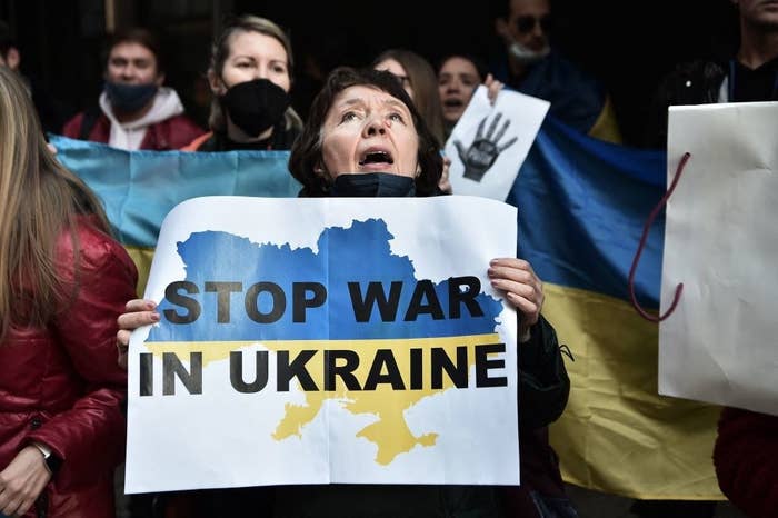 A group of protestors and a woman holding a sign that says, &quot;Stop War in Ukraine&quot;