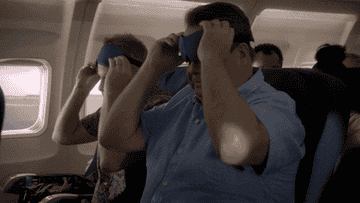 a gif of Cameron and Mitchell in the show &quot;Modern Family&quot; leaning back in their airplane seats and putting eye masks on
