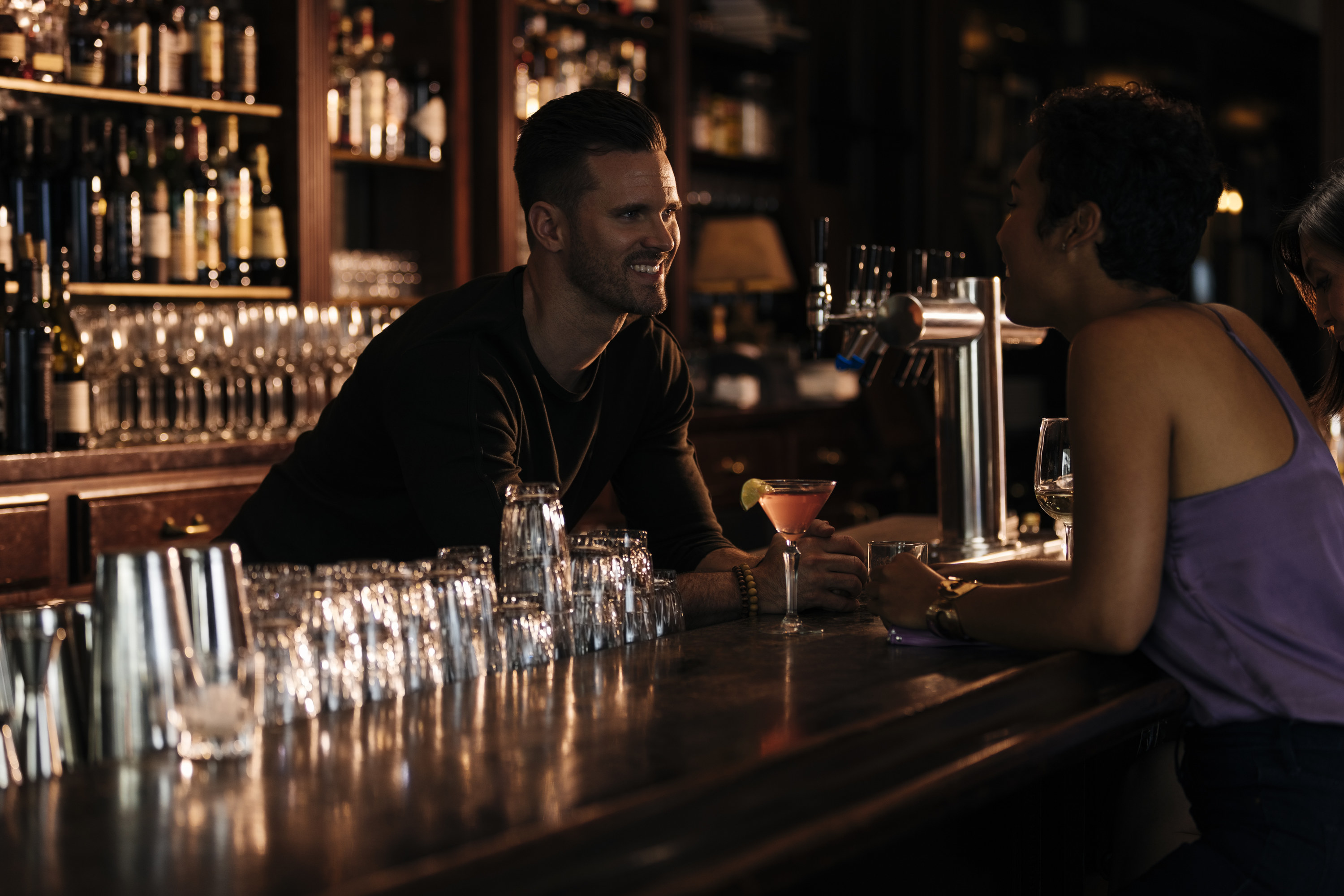 A bartender talking to a woman at a dimly lit bar