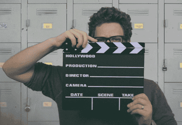GIF of man clapping a film clapper board before the scene begins