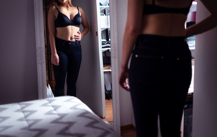 A woman looking at her body in the mirror
