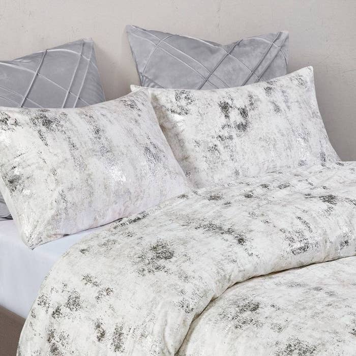 white comforter and sham pillows with silver metallic print