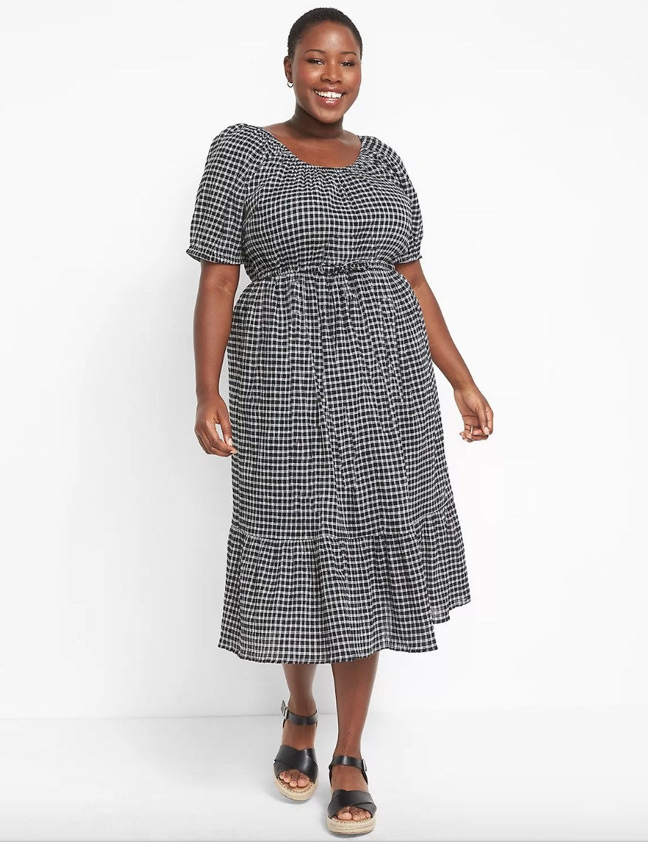 Model wearing short sleeve black and white checkered dress with black sandals