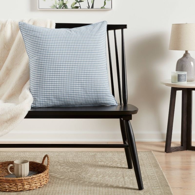 the blue gingham pillow on a black bench