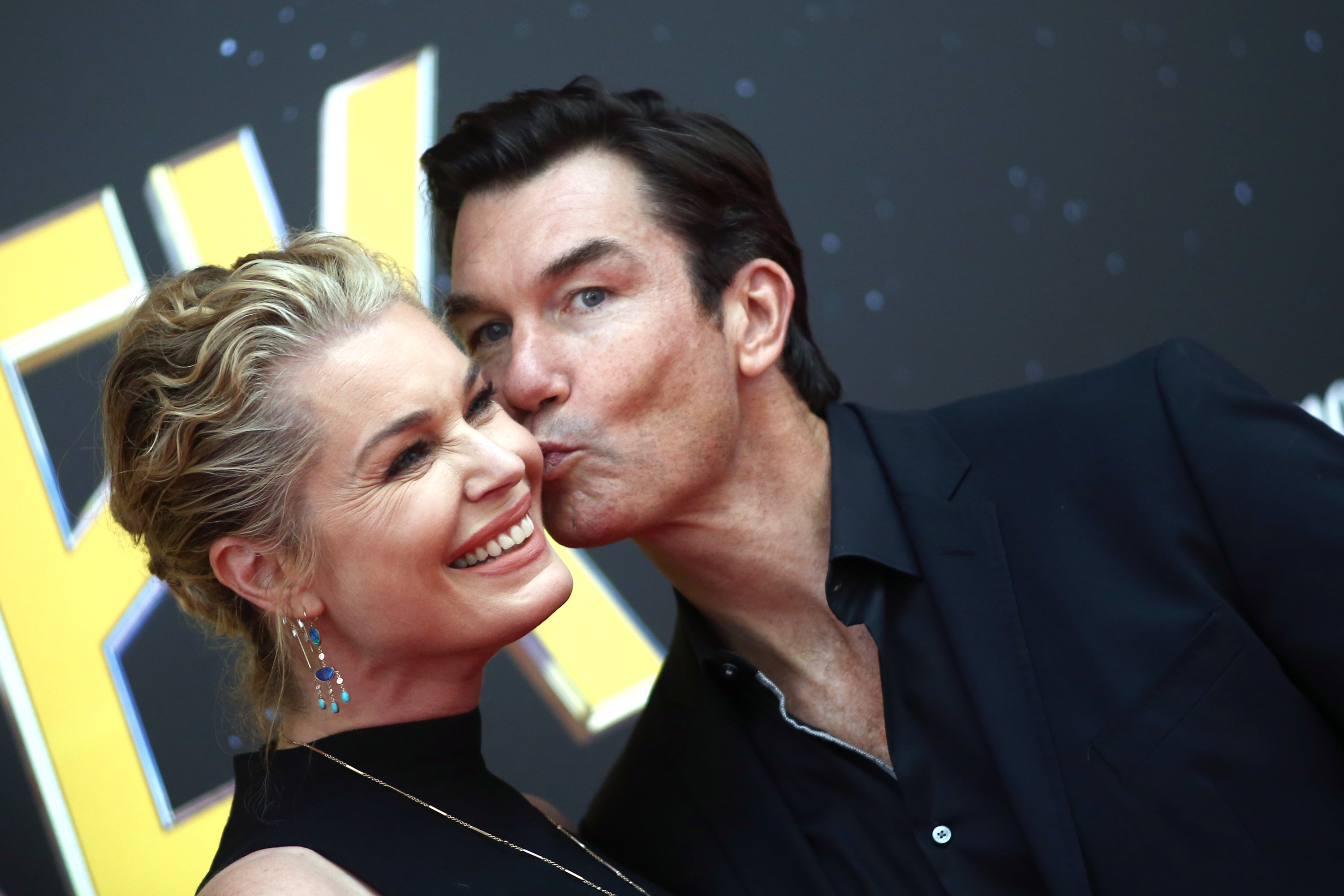 Rebecca Romijn smiles while Jerry O&#x27;Connell kisses her cheek at an event