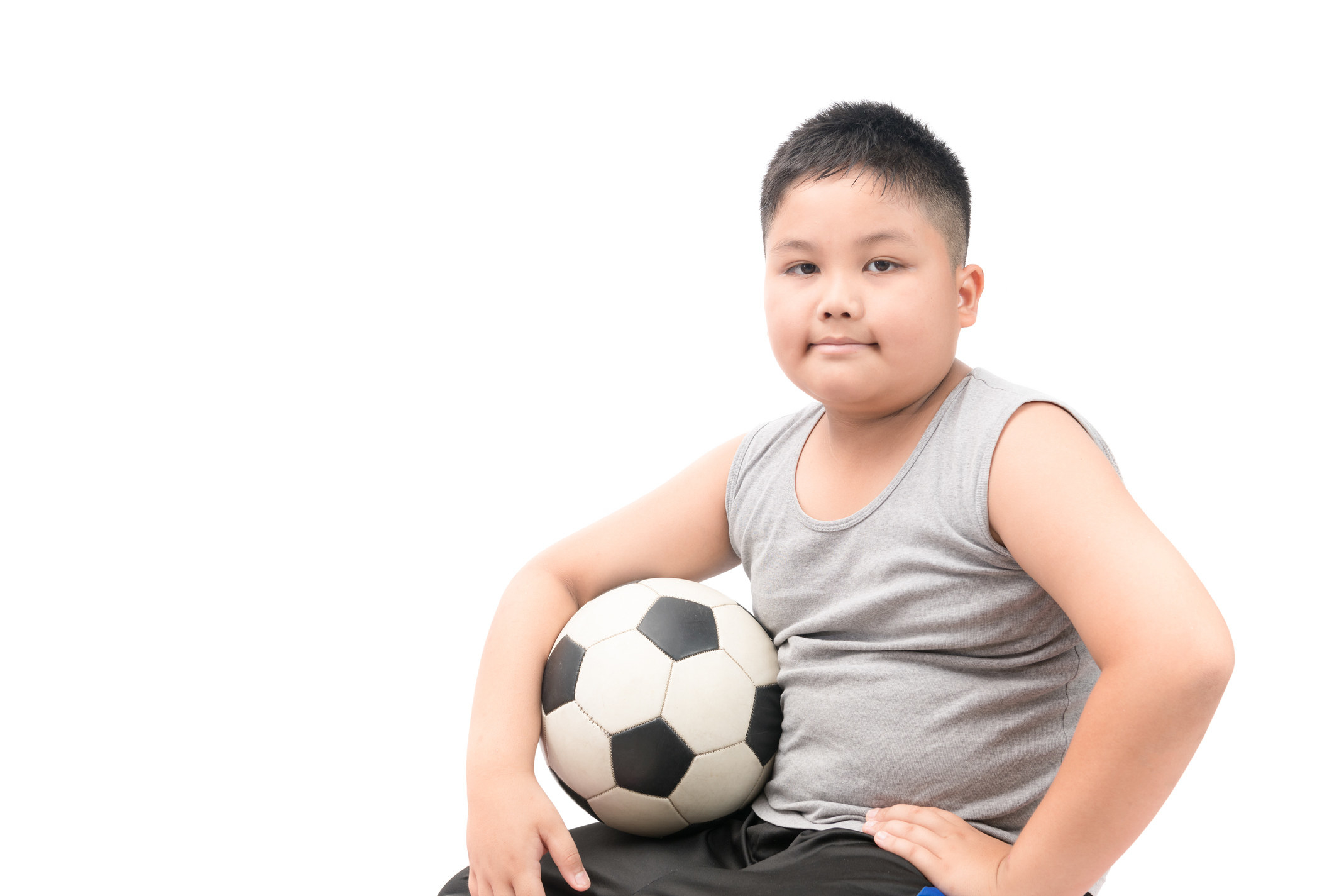 Young boy in a tank top holding a soccer ball