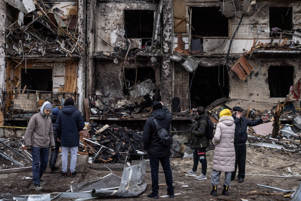 a group of Ukrainians stand in front of ruins