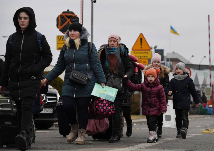 Women and children walk carrying bags