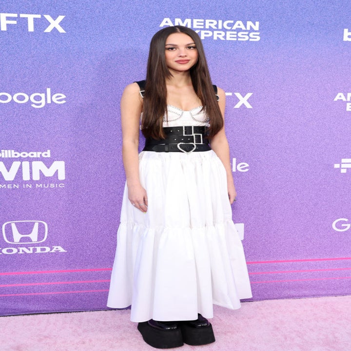 Olivia in a white dress and black leather bustier/harness with large Bratz-like platform shoes
