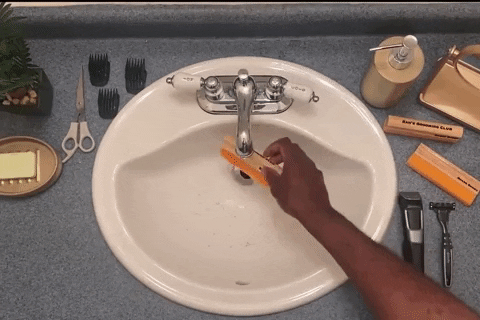 hand using the tool to clean hair from the sink