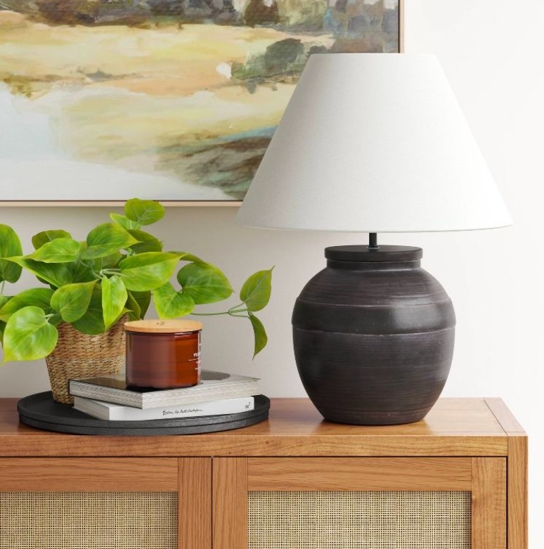 Lamp on a console with a plant, books and candle