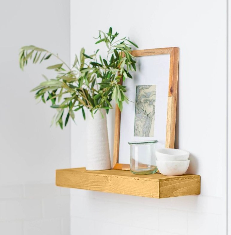Pine shelf with a picture frame, vase with greenery, bowls and a glass jar on it