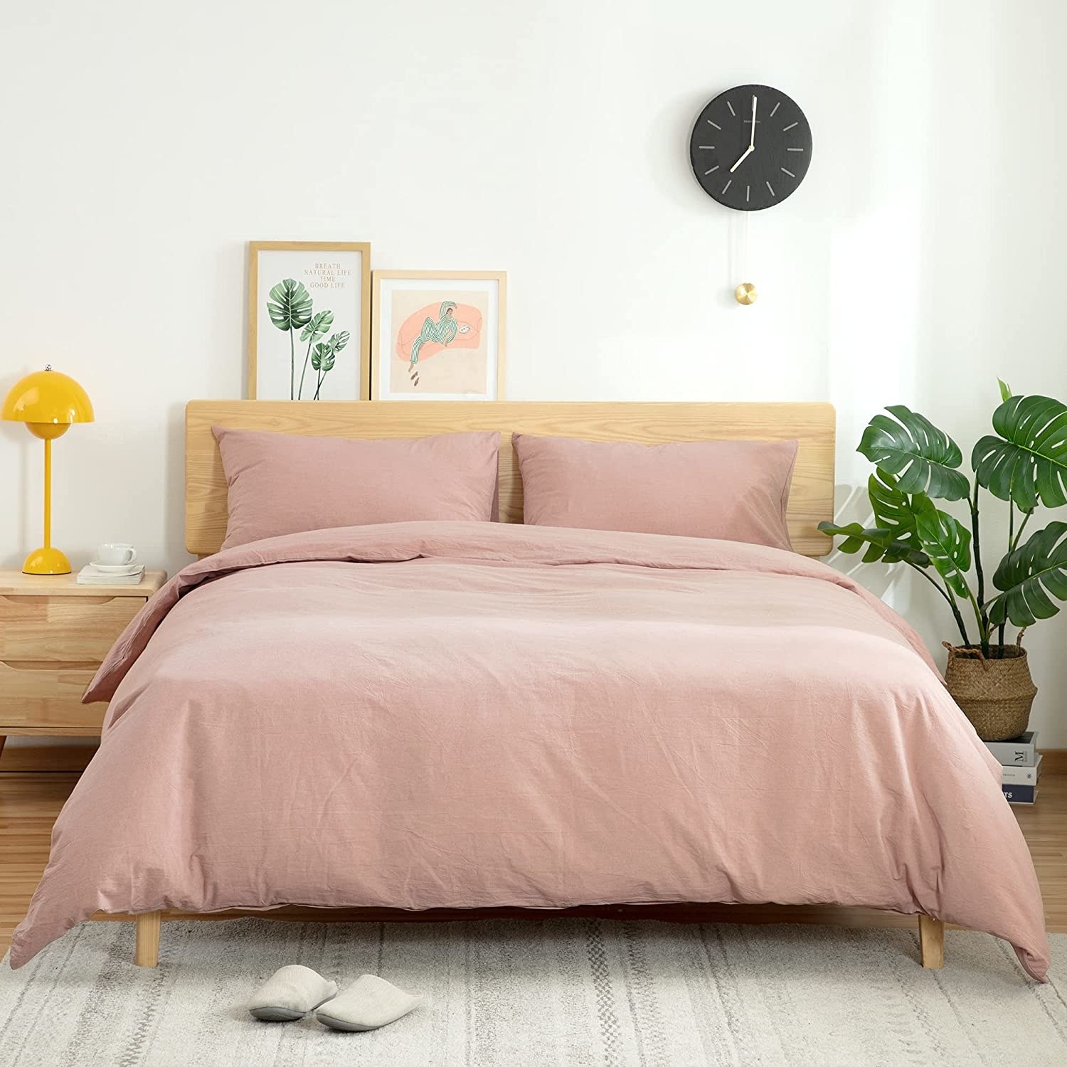 The duvet cover on a bed with a plant and nightstand on either side of it