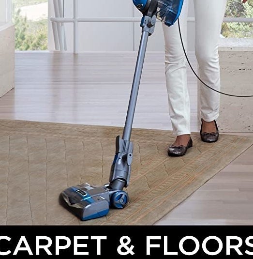 A person cleaning their floors and carpet with the stick vacuum