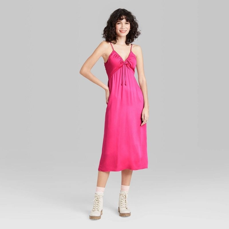 Model wearing hot pink dress, goes past the knee