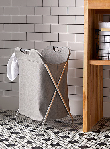 A laundry hamper on the floor of a trendy bathroom
