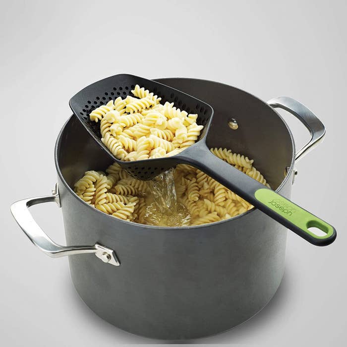 The colander scoop with pasta draining over a pot of more pasta