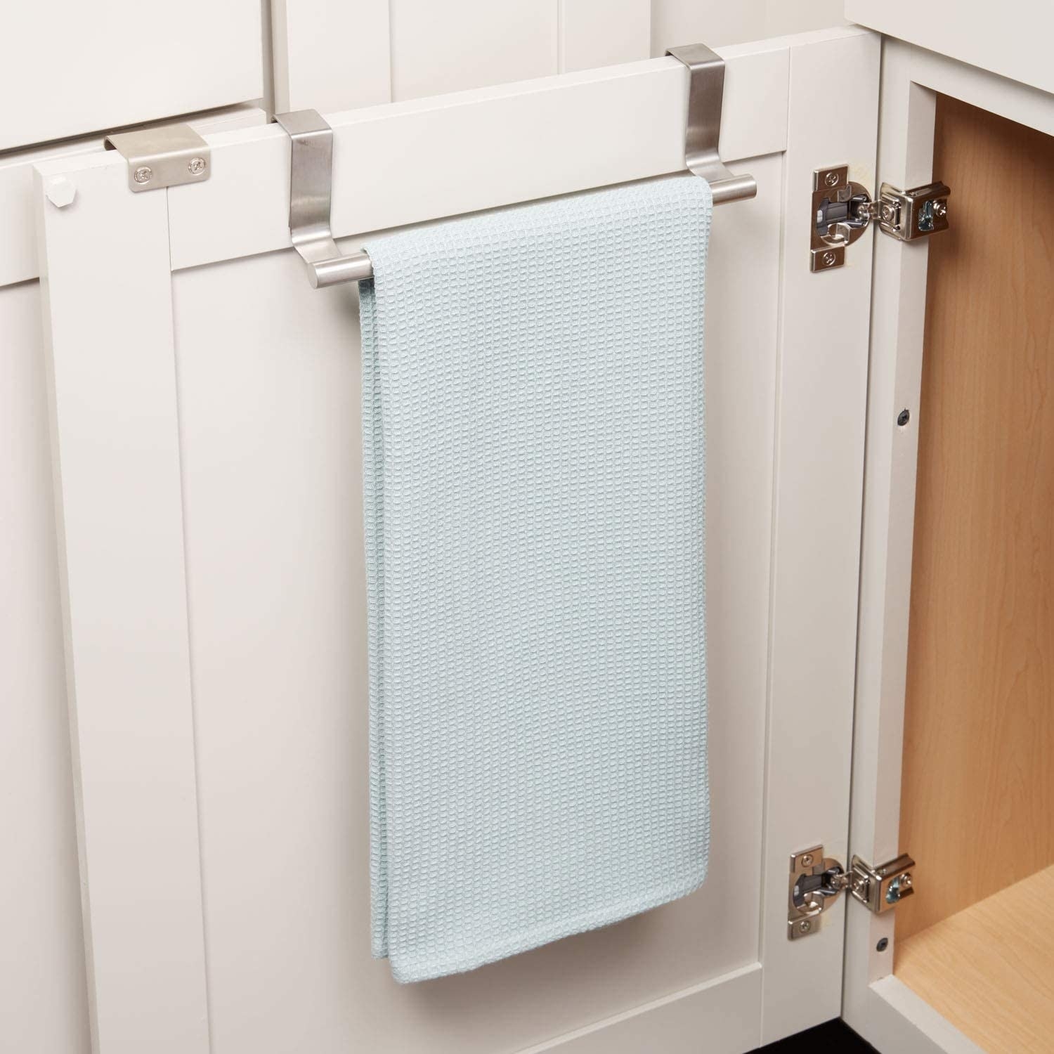 The towel bar, with a dishrag on it, hanging to face the inside of a cabinet door