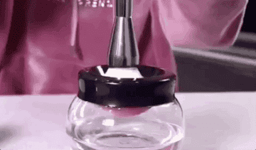 Gif of someone putting a large makeup brush into the cleaner and spinning the water to cleanse it