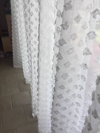 reviewer close up image of the pom poms on the sheer off-white curtains