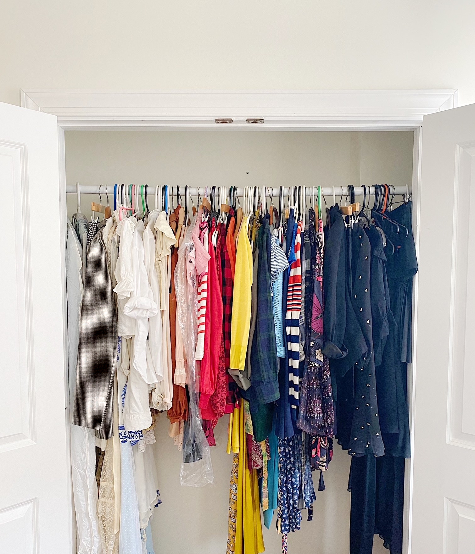 the inside of BuzzFeed writer Britt Ross&#x27; closet showing clothes arranged by color