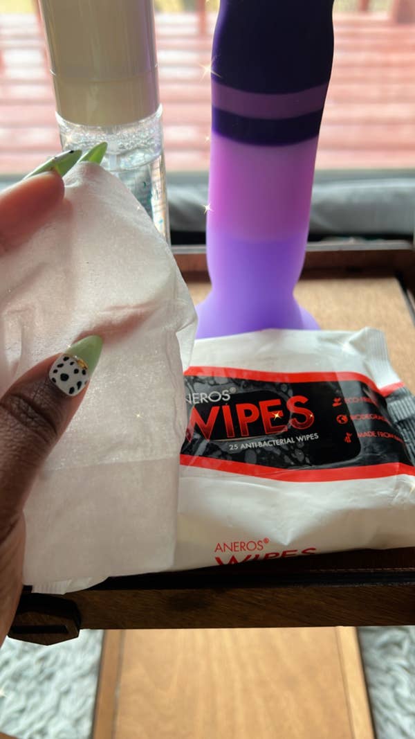 Hand holding wipe in front of dildo
