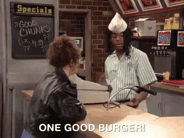 young man working behind the counter telling one customer &quot;one good burger&quot;