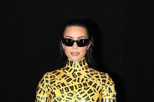 Kim holds her purse while wearing the caution tape dress