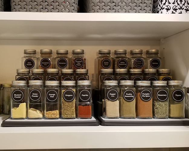 reviewer photo of spices lined up on the tiered spice rack inside a cabinet