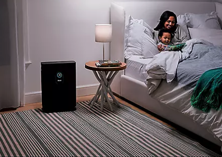 a mother and child read a book in bed next to the purifier