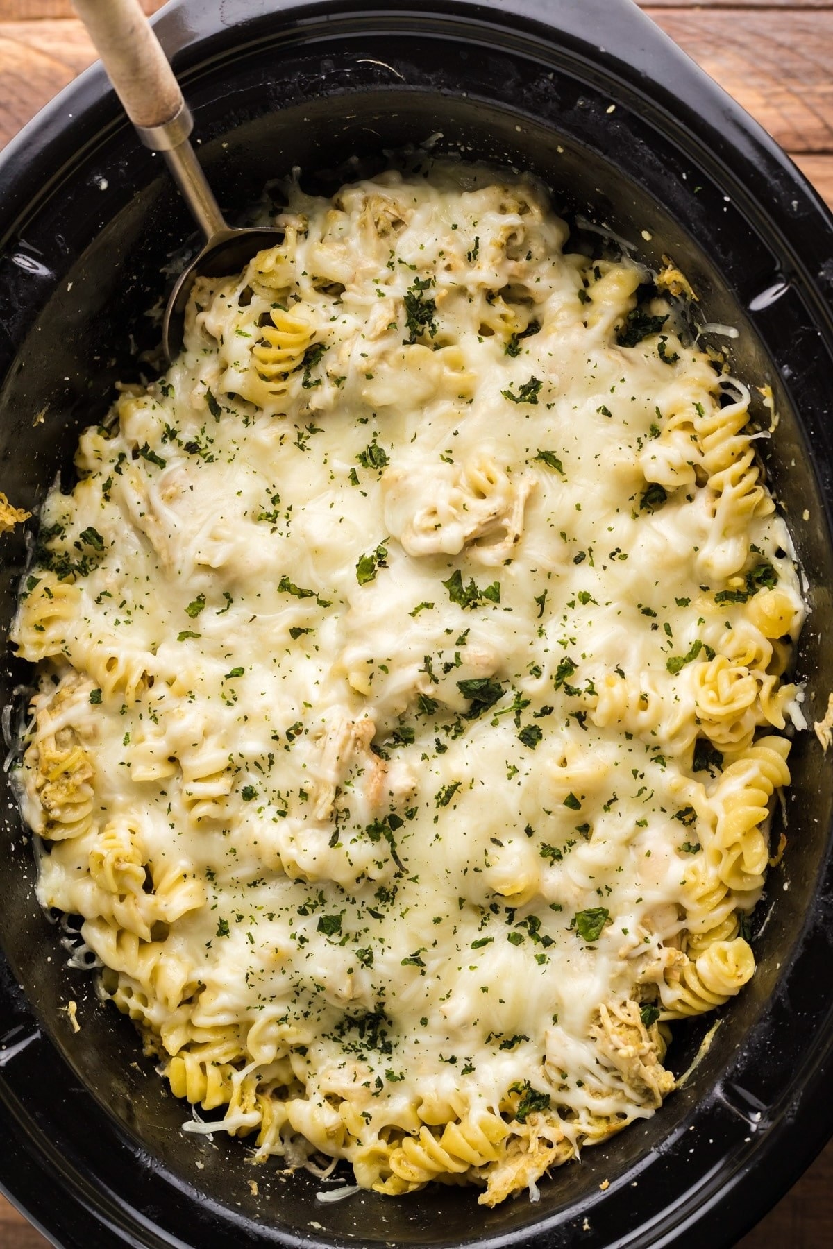 A slow cooker filled with cheesy pesto pasta.