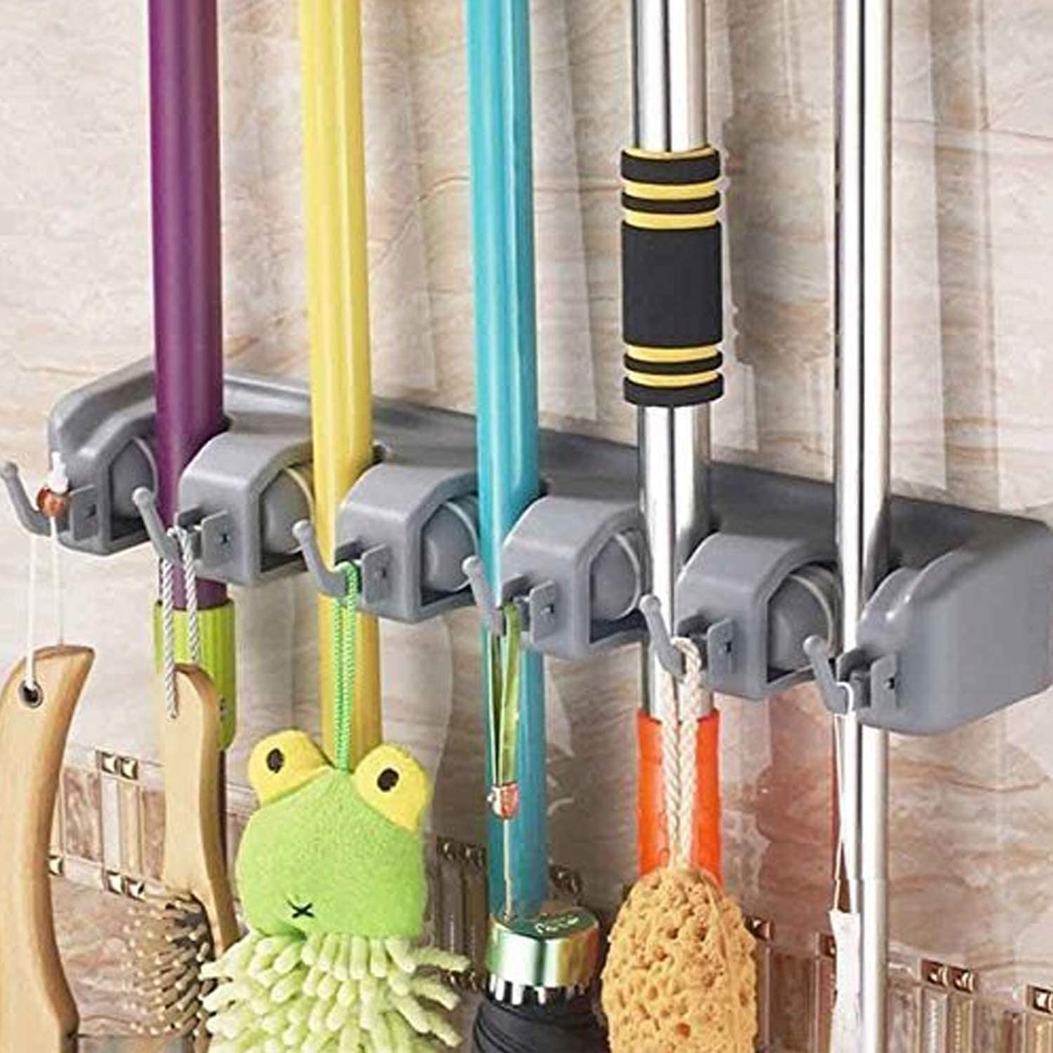 The broom holder hung up on a wall with mops and brooms in all five slots