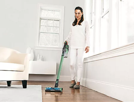 a woman uses the vacuum on a wooden floor