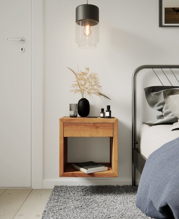 The floating nightstand mounted on a wall next to a bed