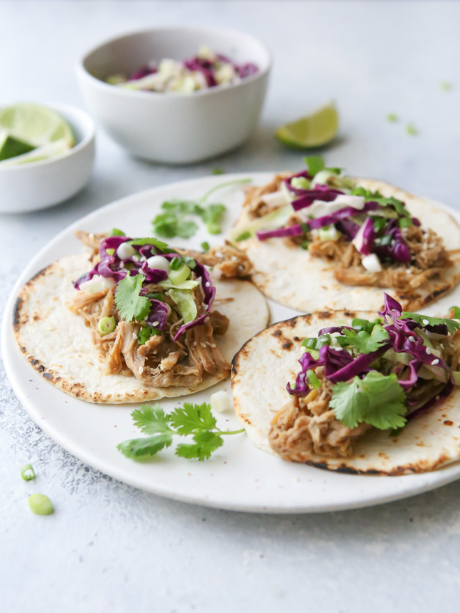 Tortillas topped with shredded pork, cabbage, and cilantro.